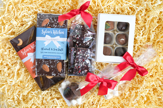 Small holiday gift box, which includes 2 full-size gourmet chocolate bars, 6-piece box of assorted truffles, nostalgic peppermint chocolate bark, 2 hot chocolate pops. 